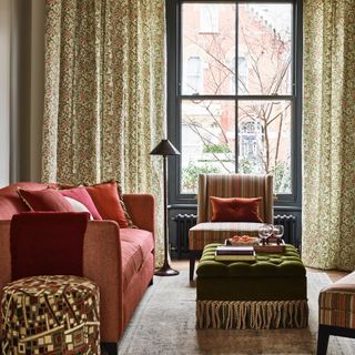 living room colour schemes, rust and green living room with green leaf design curtains, footstool with fringing, grey painted woodwork, cushions, cosy