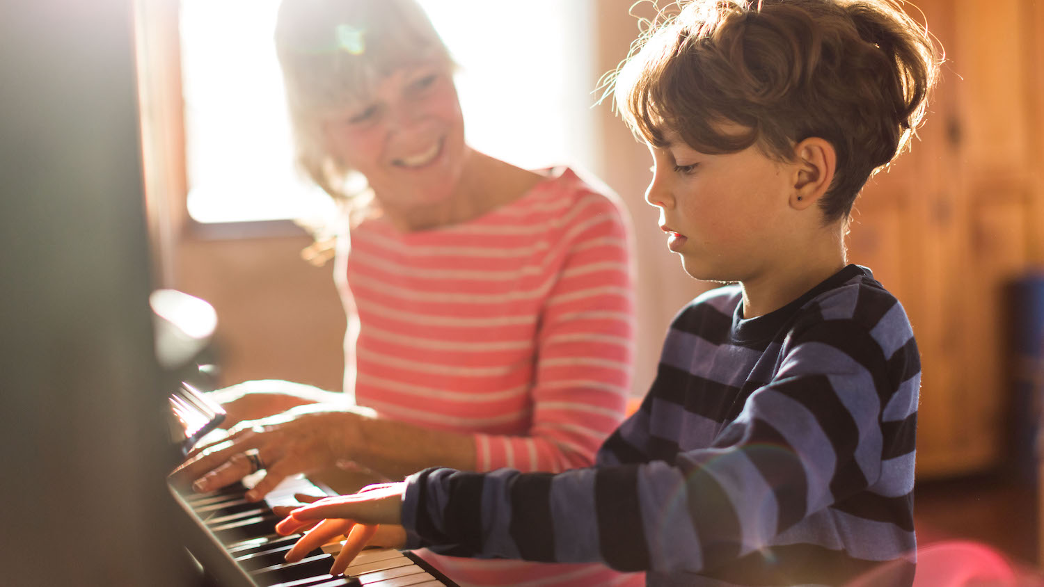 child sits with woman on an acoustic piano
