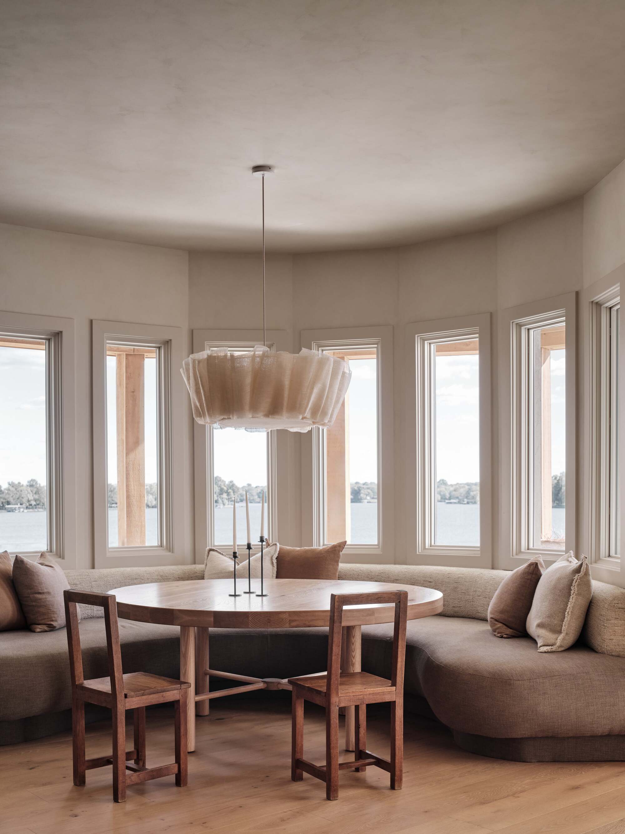 curved banquette seat in the window around a round dining table with two dining chairs and a pendant light hanging overhead