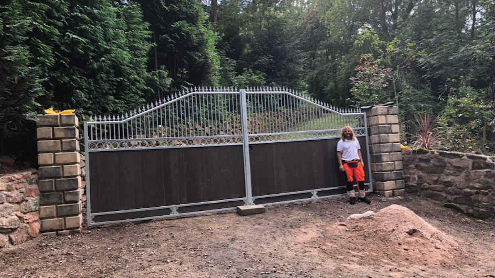 A large set of metal gates with a woman standing in front of them