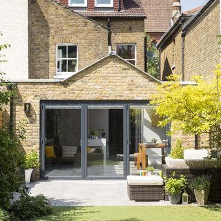 Brick house patio with bifold glass doors and back lawn