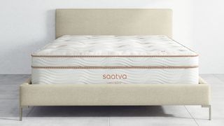 The Saatva Latex Hybrid, the best Saatva mattress for hot sleepers, is photographed here on a plain cream bedframe in a white bedroom with white floors