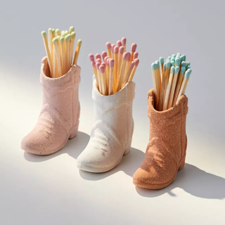 Trio of white, pink, and terracotta ceramic cowboy boots holding matches