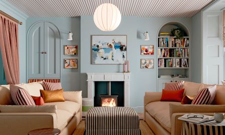 Light blue living room with beige striped ceiling, black and white striped ottoman, beige sofas and artwork