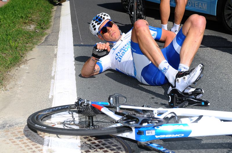 A Novo Nordisk rider on the ground after a crash in the peloton