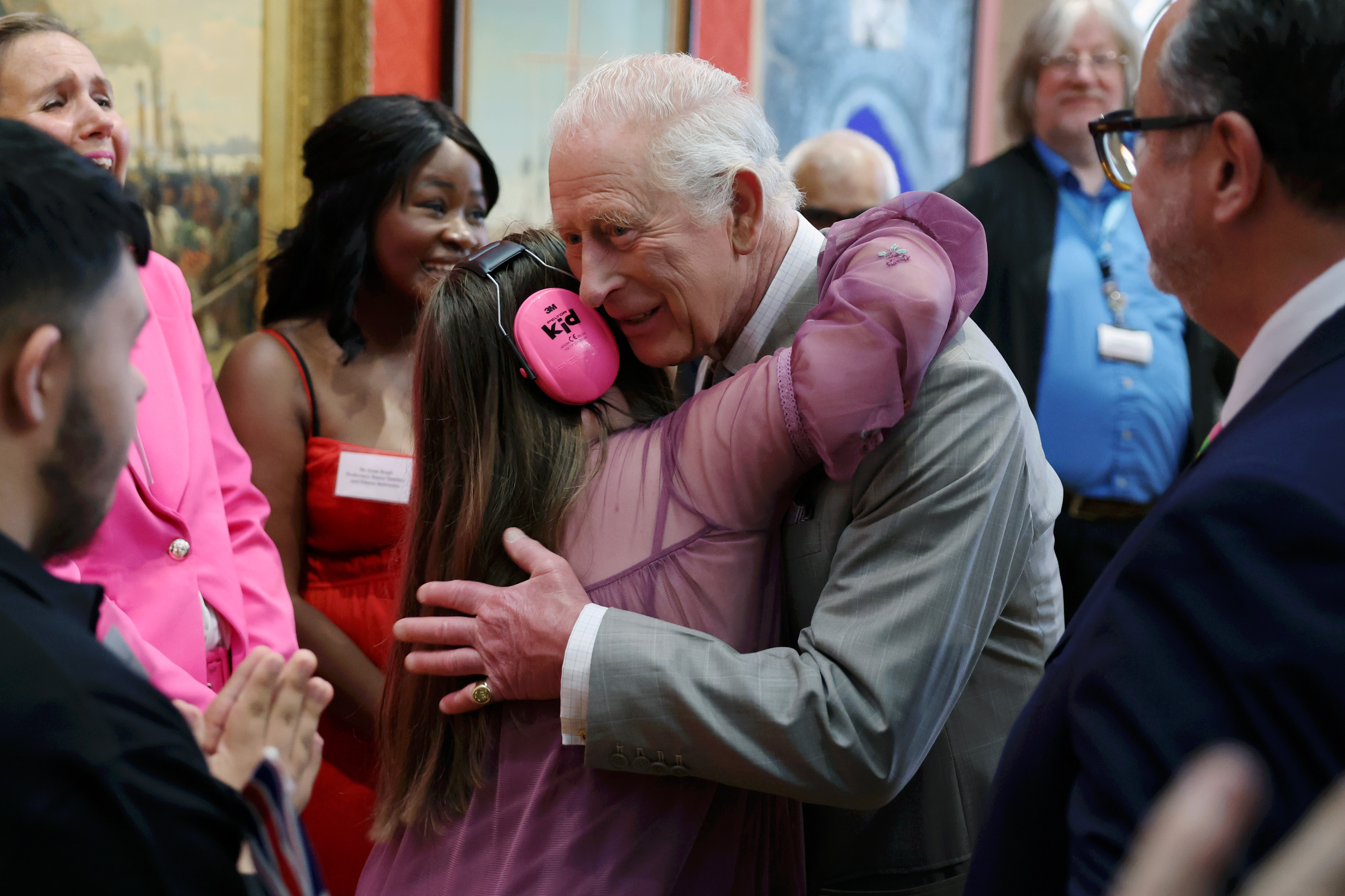 The King hugging a girl wearing pink headphones