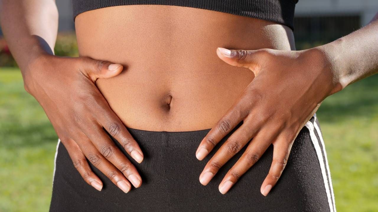 Woman placing her hands on her stomach, sleep &amp; wellness tips