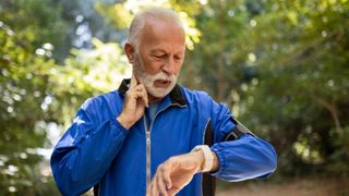 an elderly man checking his pulse by holding two fingers to his neck and checking the time on his watch