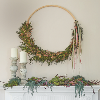 Sophisticated Christmas decorations, with metallic and magical finishes, modern wreath ring, above a mantlepiece and fireplace.