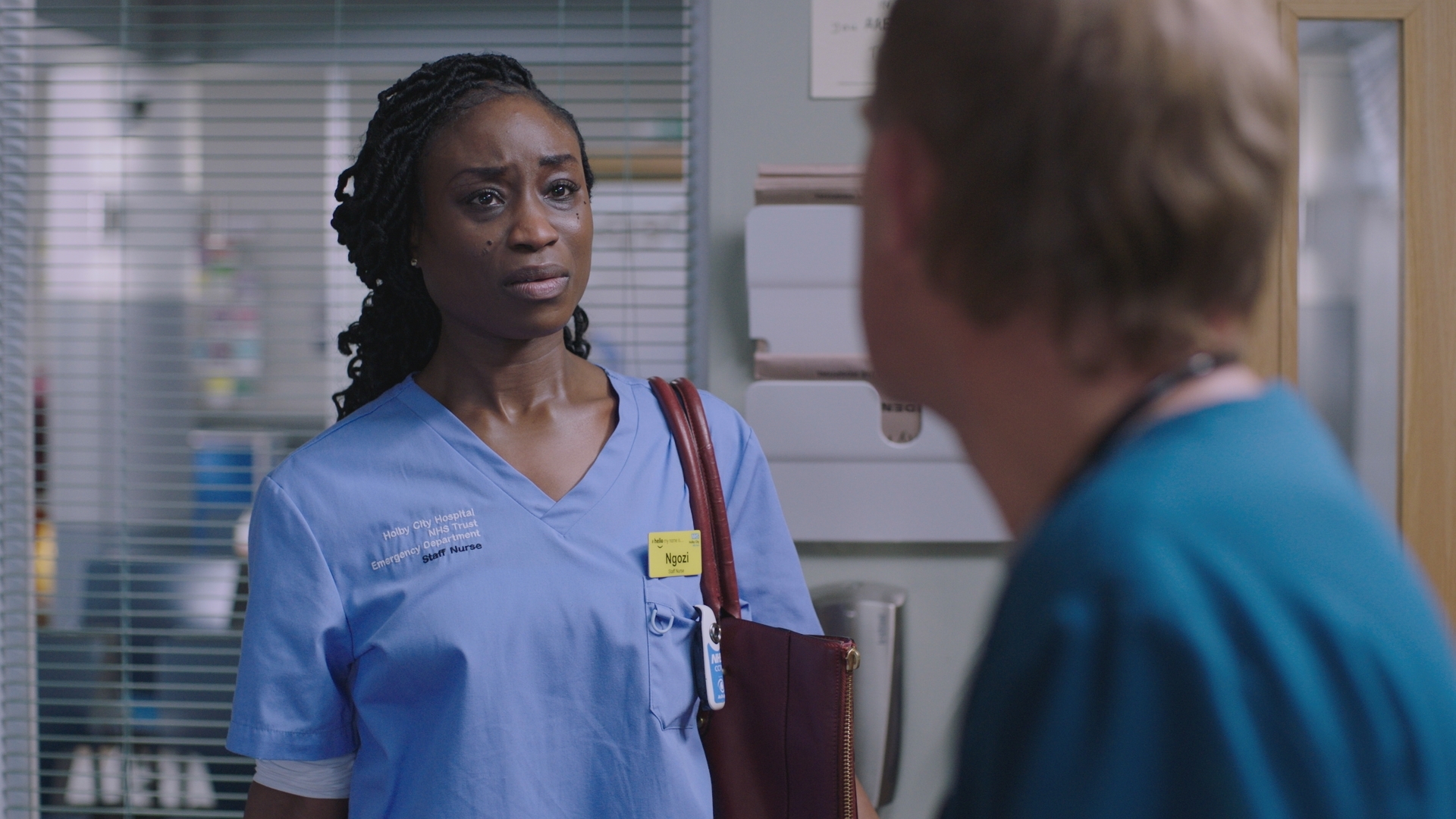 Dylan talks to Ngozi while she wears her handbag on her shoulder.