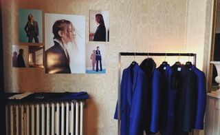 Navy coats hanging on a rack next to pictures on a wall