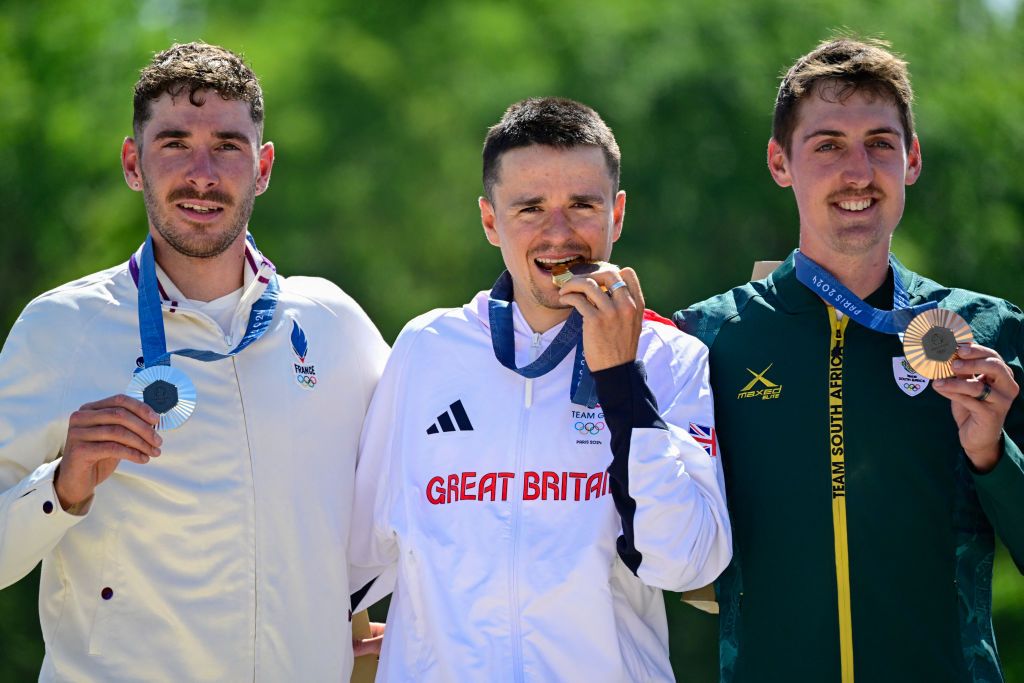 (From L) Silver medallist France's Victor Koretzky, gold medallist Britain's Thomas Pidcock and bronze medallist South Africa's Alan Hatherly celebrate on the podium after the men's cross-country mountain biking event during the Paris 2024 Olympic Games in Elancourt Hill venue in Elancourt, on July 29, 2024. (Photo by John MACDOUGALL / AFP)