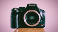 Canon EOS Kiss Digital sitting on a wooden surface