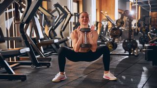 Woman doing sumo goblet squat in gym