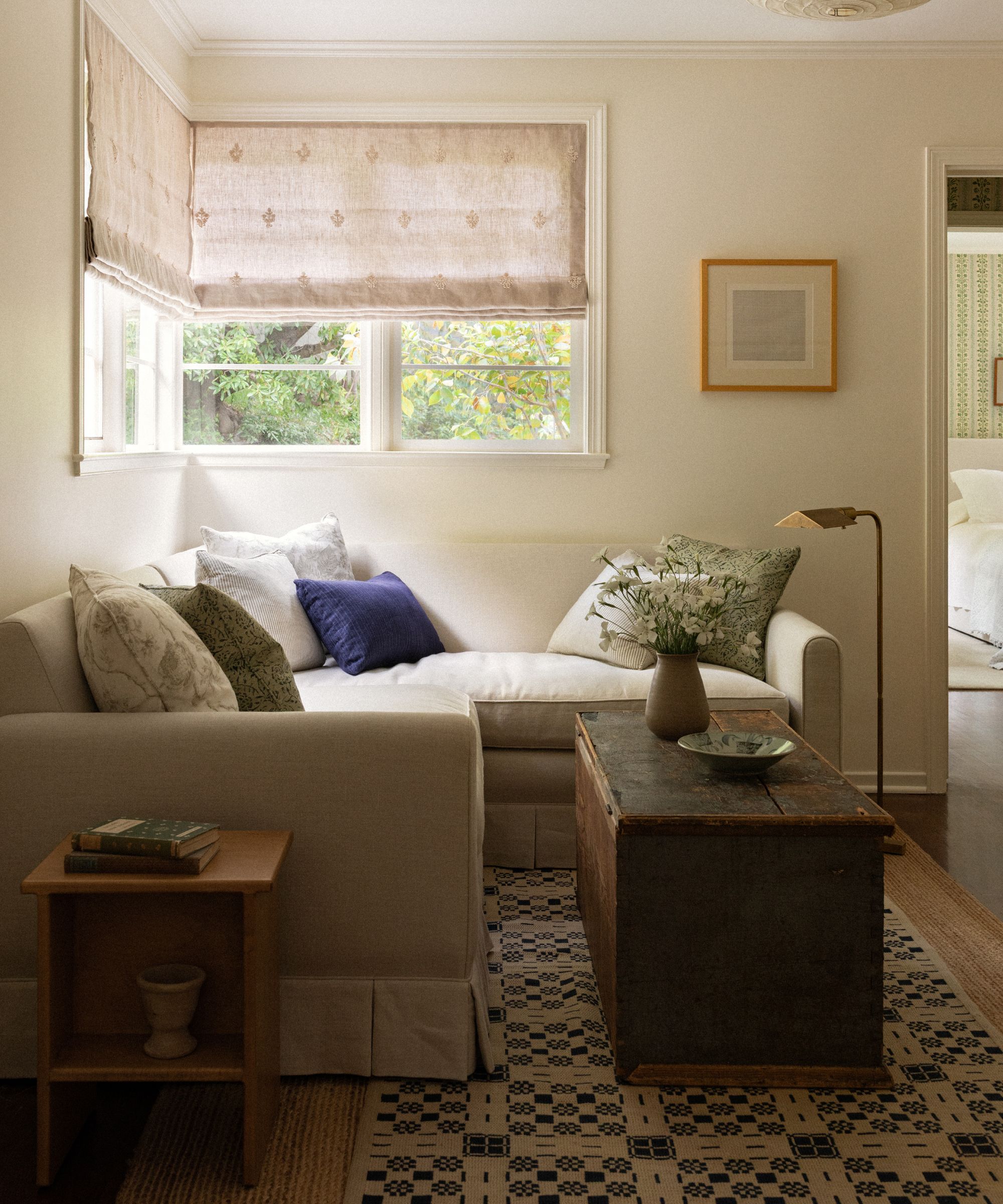 an upstairs sitting room with a skirted corner couch, antique wooden coffee table and vintage rug