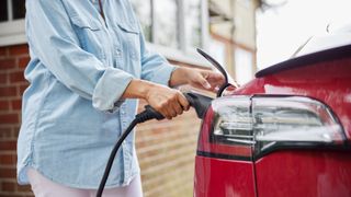 Woman charging an electric at home following olev grant success