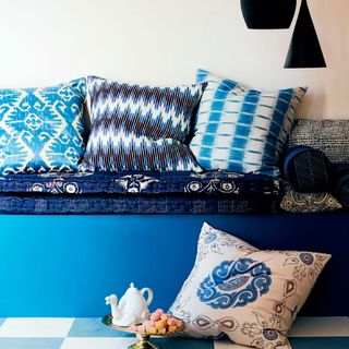 room with blue couch and cushions on pattern floor