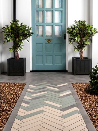 small front garden ideas: walls and floors tiled pathway leading to blue front door with small trees in planters either side