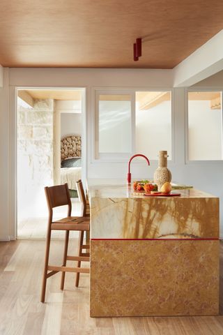 a kitchen with a marble island and red faucet