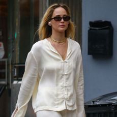 Jennifer Lawrence walks down the streets of New York wearing a cream satin two-piece with mesh ballet flats and a Dior Saddle bag.