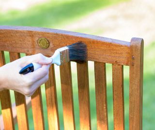 applying wood stain to a wooden outdoor chair