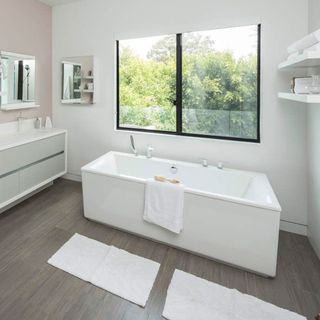 master bedroom with white wall and towel on bathtub