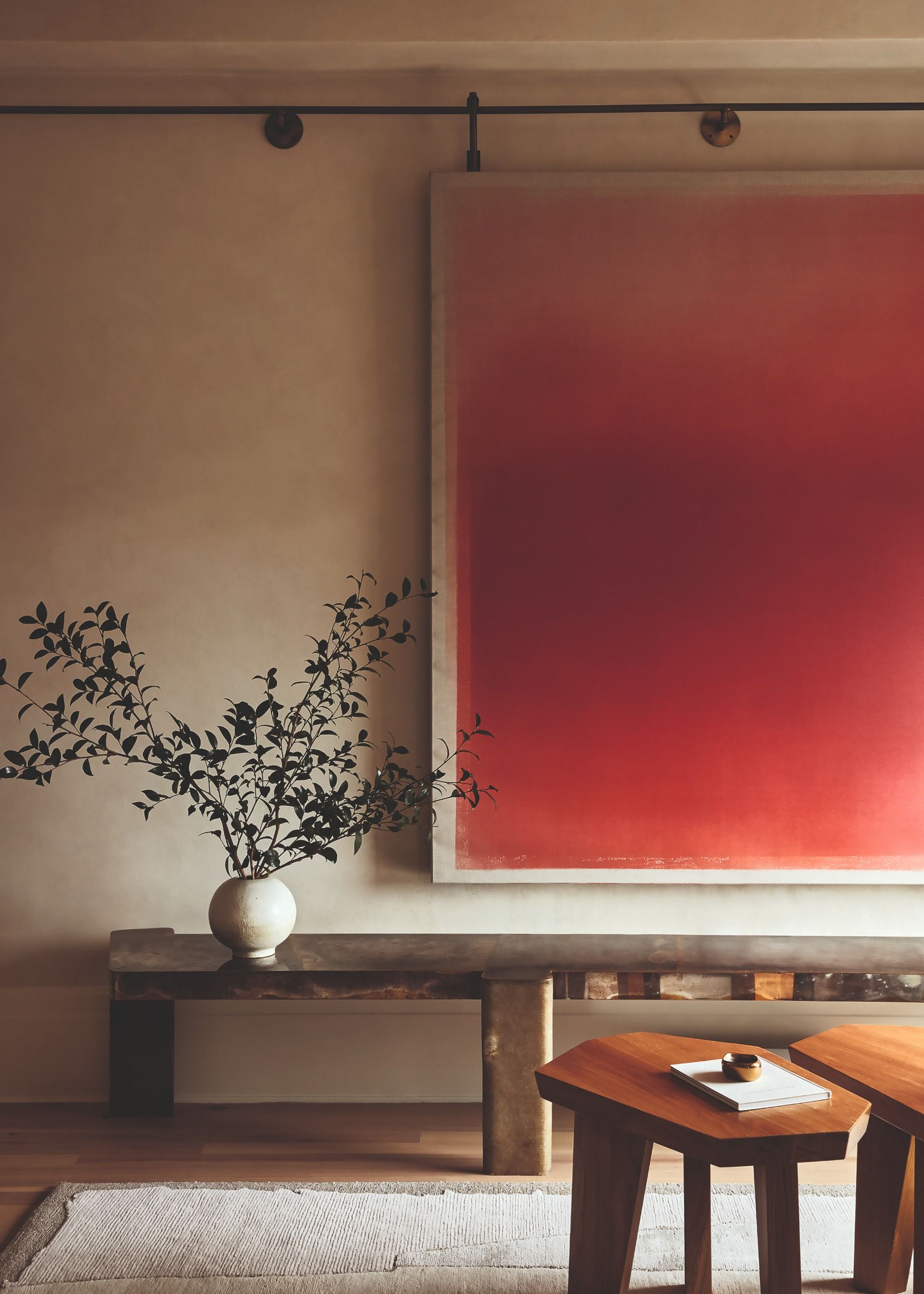 a large red canvas on a moveable rail with a low console table and side tables in front 