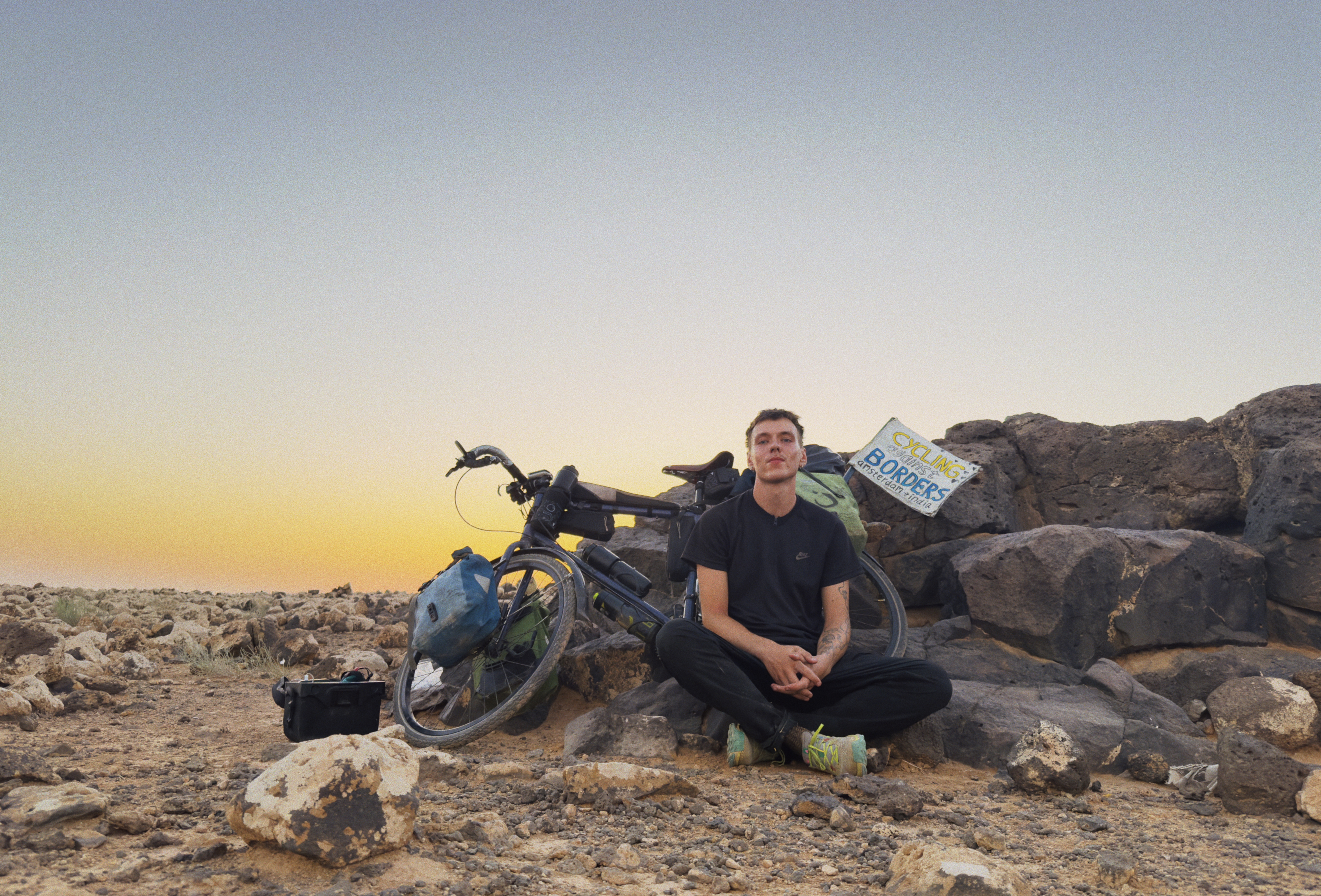 Man sits next to bike and rocks