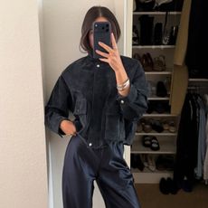 Ivana wears a black bomber jacket and navy satin trousers