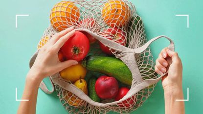 woman reaching into a bag of fruit and vegetables