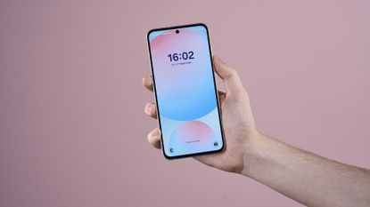 Samsung Galaxy S24 FE held in someone's hand with display showing the time