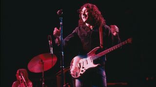 Rory Gallagher in 1975, onstage with his number one Strat, holding court with the audience.