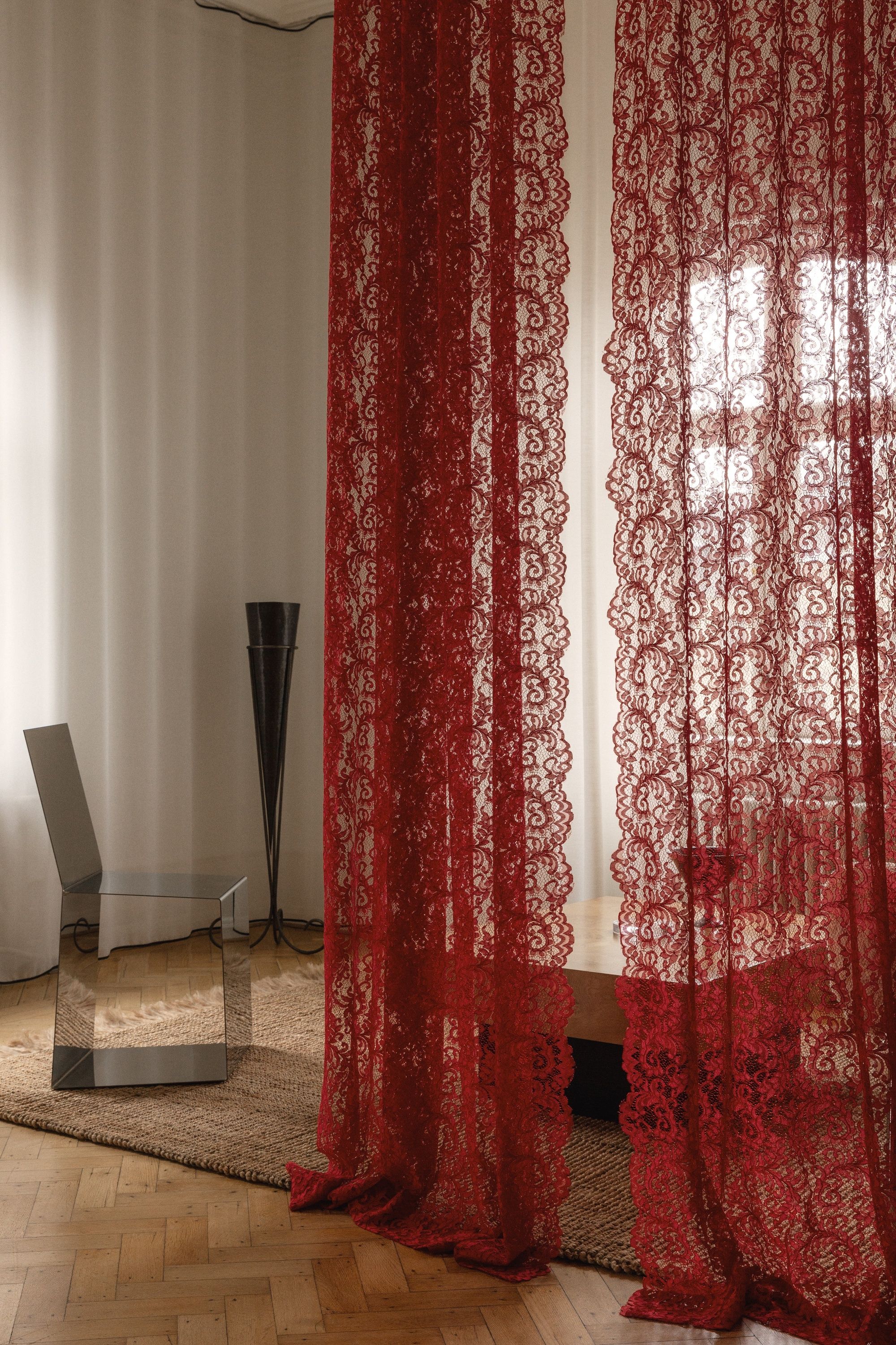 red lace curtains hanging in the middle of a room in a heritage building in Copenhagen with parquetry floors and sheers on the windows