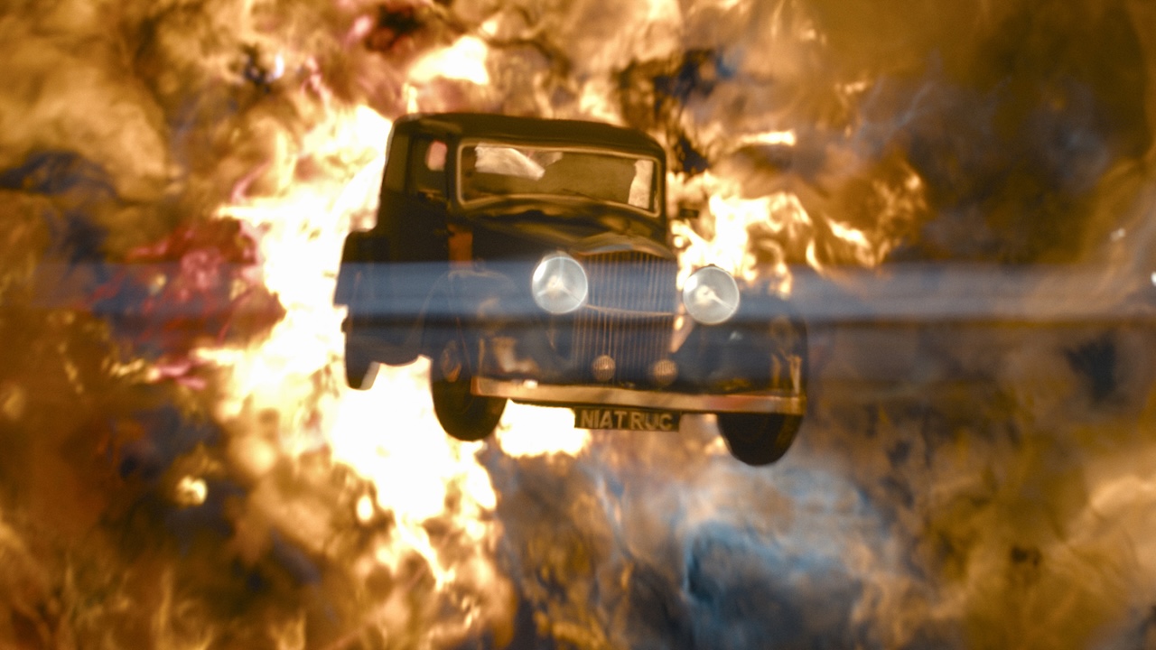 Crowley's Bentley flying through the air with a giant fireball behind it in Good Omens Season 3