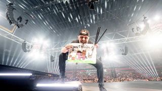Lars Ulrich onstage holding a handmade Metallica sign 