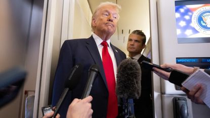 US President Donald Trump speaks with the media as Defense Secretary Pete Hegseth looks on aboard Air Force One during a flight from Dover, Delaware, to Miami, Florida, on March 7, 2026. (Photo by SAUL LOEB / AFP via Getty Images)