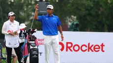 Hideki Matsuyama picking out a club with caddie Mei Inui standing on the tee at the 2025 Rocket Classic