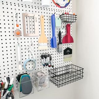 A pegboard with tools and paintbrushes on it