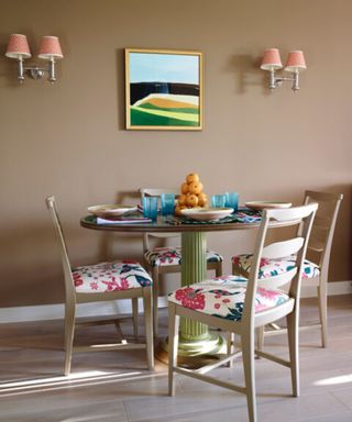 A beige dining space with light pink painted chairs and table
