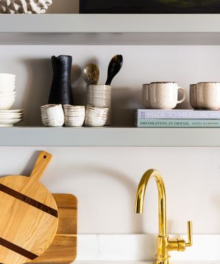 kitchen shelving with utensils, cups and books with cutting boards