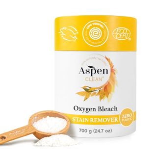 A yellow and white cylindrical cardboard box of Unscented Oxygen Bleach Powder and Color Safe Stain Remover by Aspenclean with a wooden scoop of laundry powder