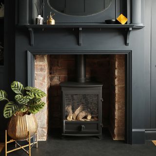 A black-painted fireplace fitted with a wood-burning stove matching with the walls