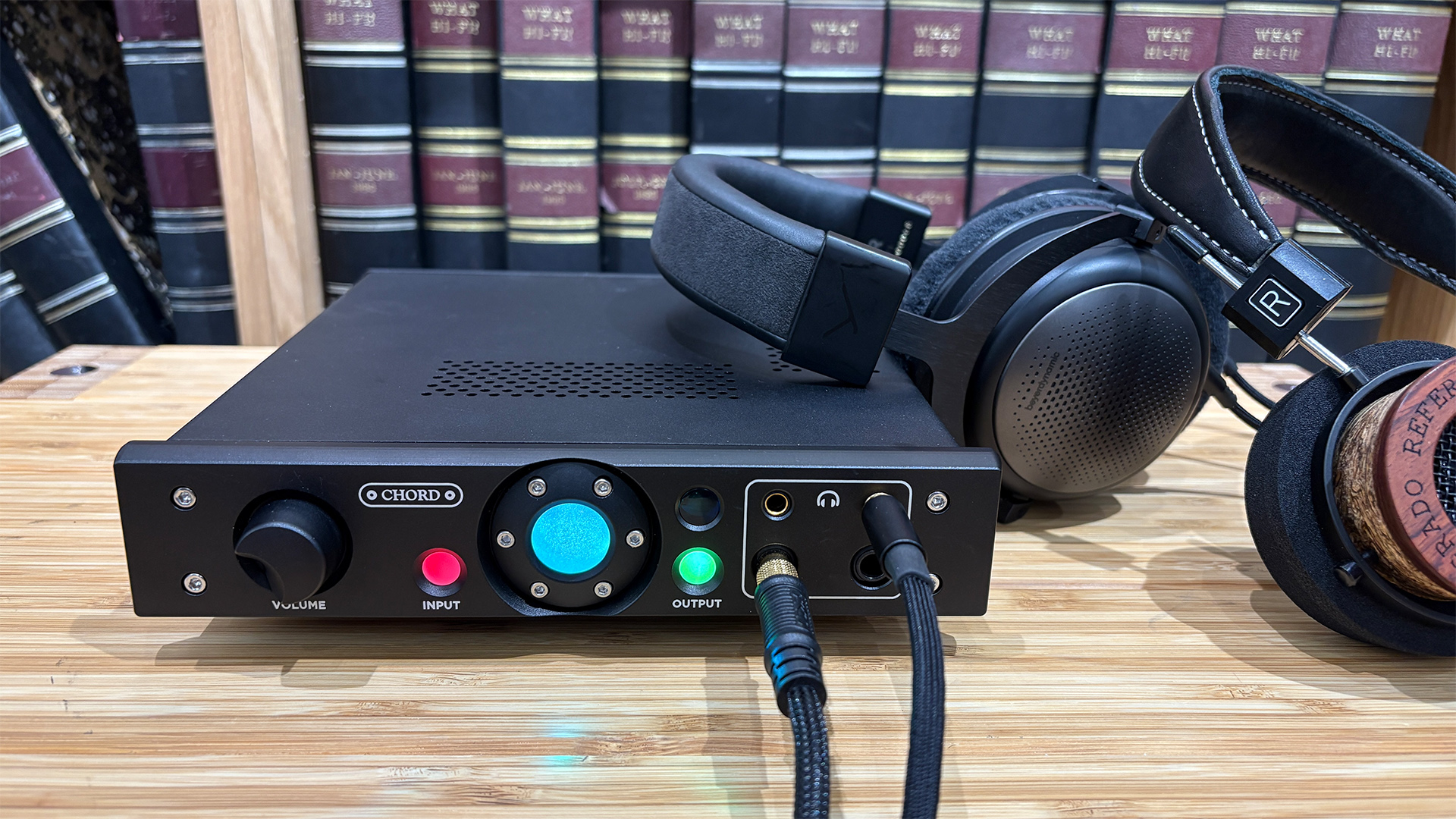 Chord Electronics Alto headphone amp in front of bookcase with two pairs of headphones connected