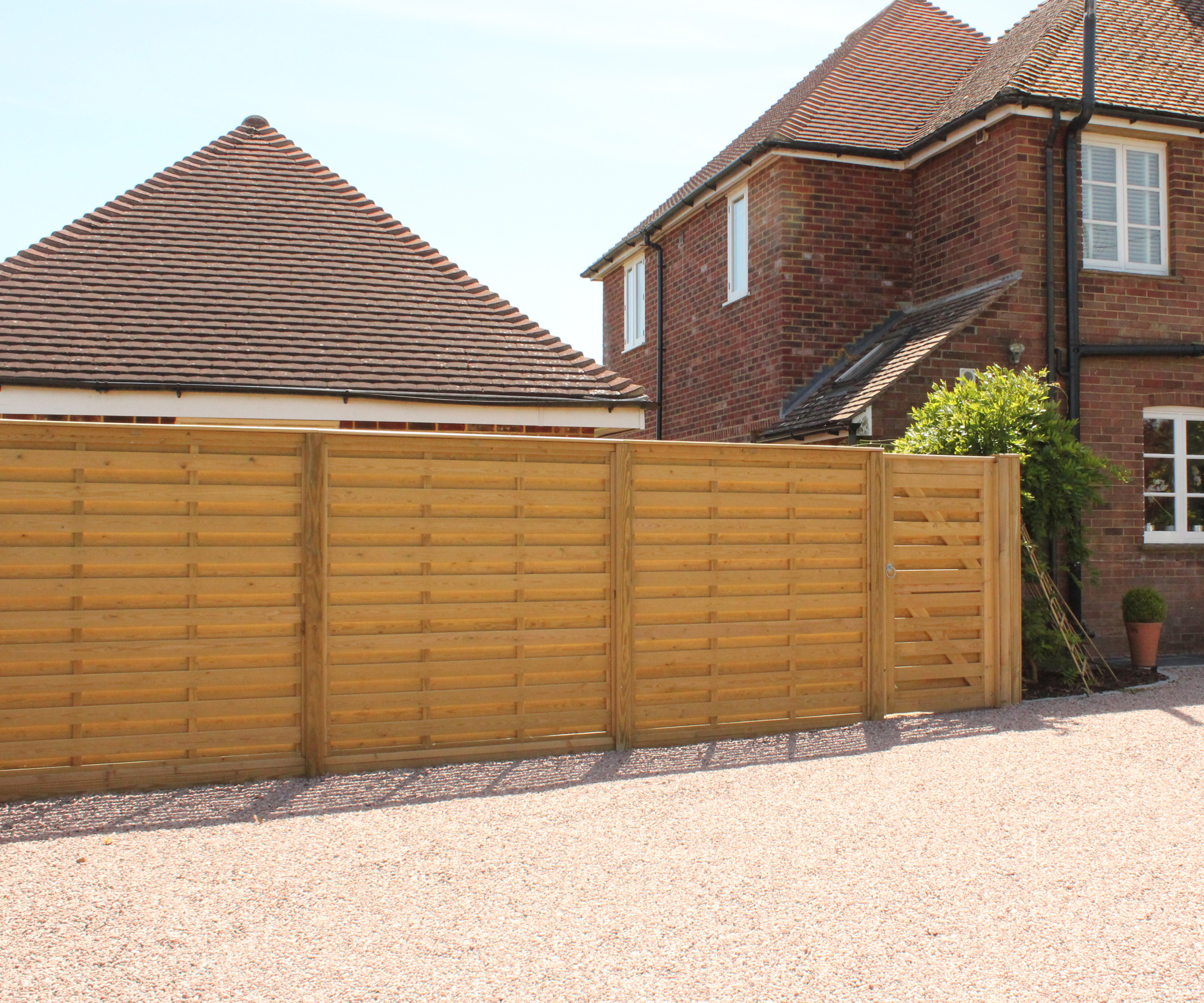 gravel driveway with wooden hit and miss horizontal fencing including gate