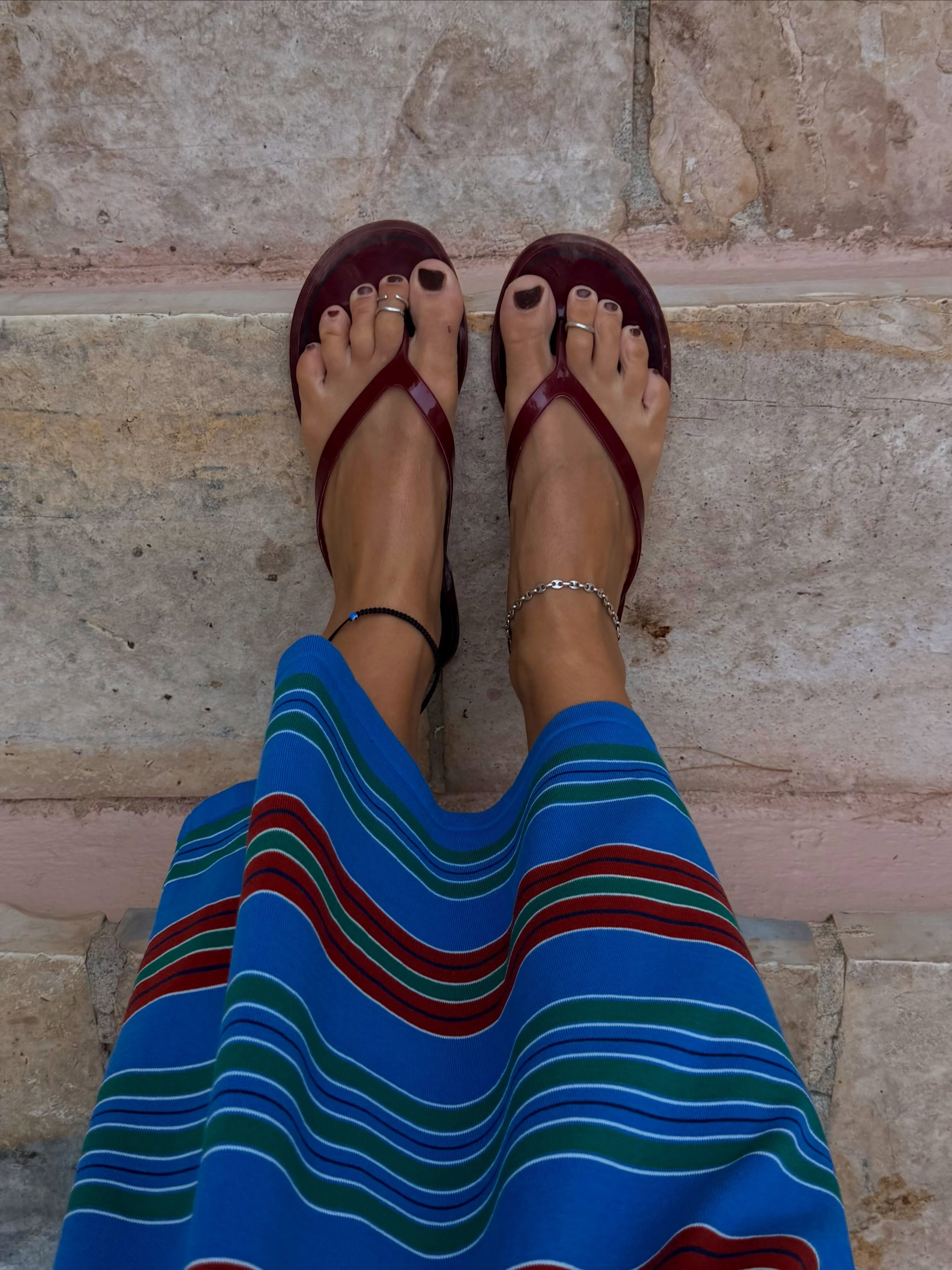 Lucy Williams wears a stripey skirt, flip flops, anklets and toe rings summer fashion trends 2026