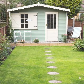 Garden with lawn and stepping stones making their way up to a summer house