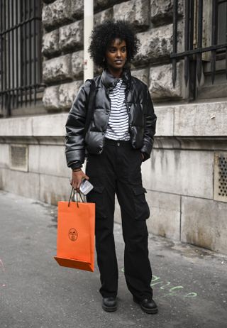 woman wearing cropped puffer jacket, striped shirt, pants, and boots