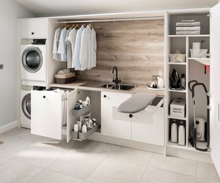 wall of white utility cupboards with washer, dryer, hanging rail, integrated ironing board
