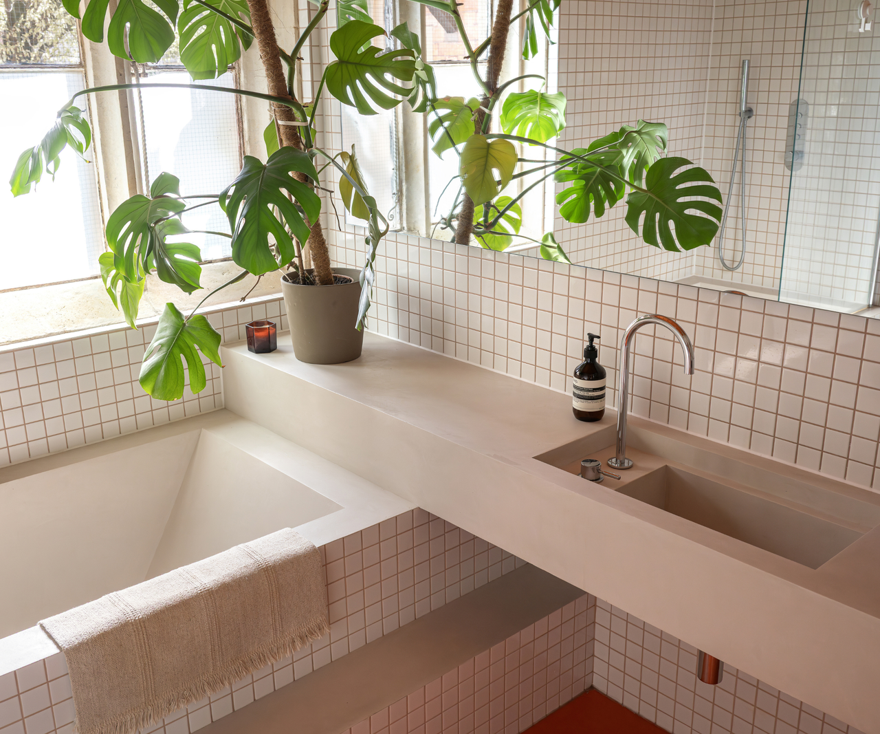 Close up of the bathroom which features small white square tiling and constrasting grout on walls and bathtub