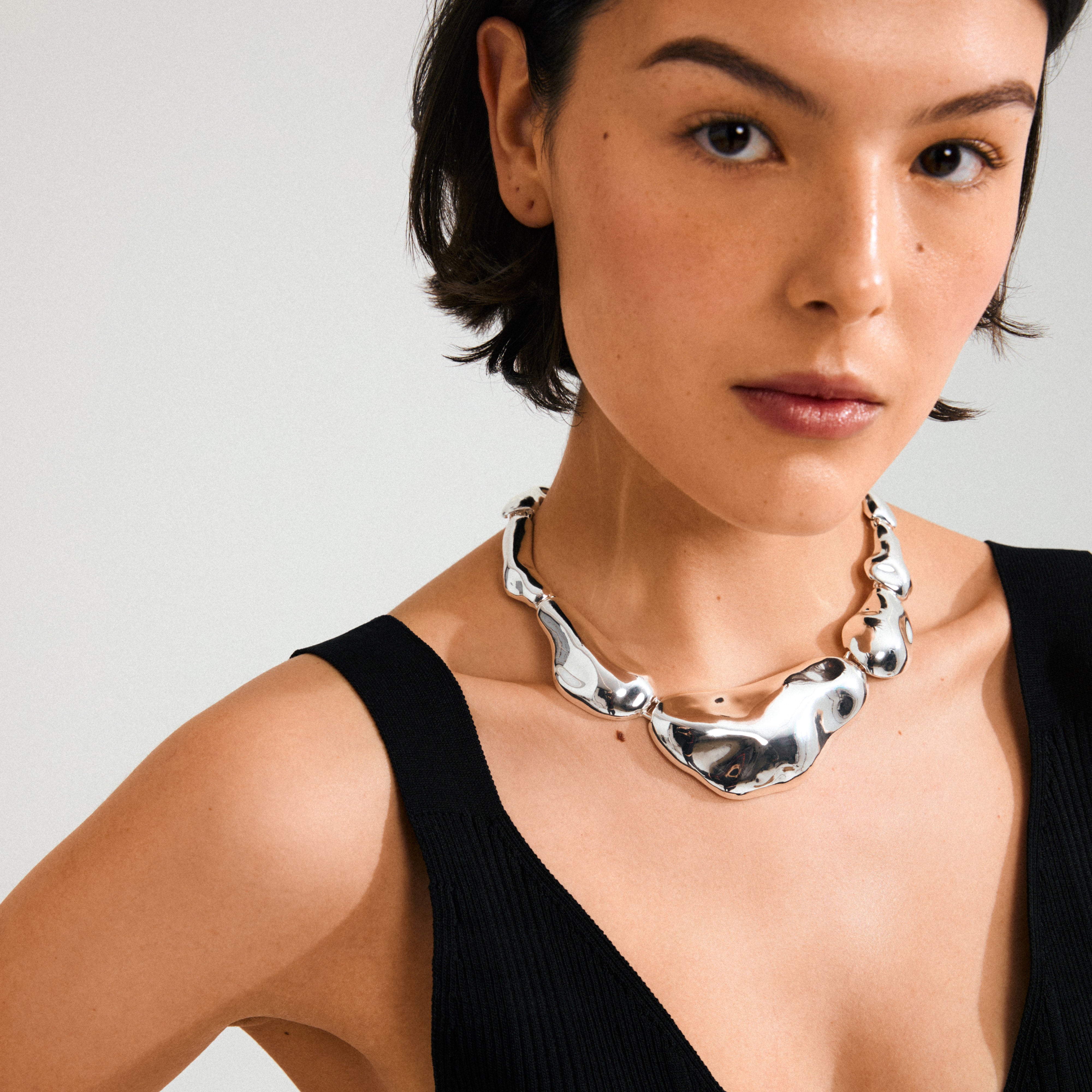 a model wearing a silver sculptural necklace from pilgrim